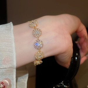 Detailed view of an 18k gold-plated flower bracelet with sparkling cubic zirconia on a wrist