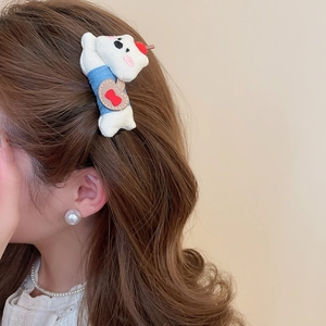 Detail view of a cute plush puppy hair clip worn on hair with soft blue fabric textures