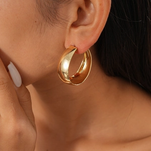 Close-up of a minimalist multi-layered gold geometric circular earring worn by a model