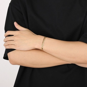 Close-up of a gold-plated titanium cuban link chain bracelet worn on a model's wrist