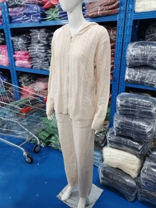 Dettaglio della trama a trecce e della zip in metallo sulla tuta beige con cappuccio