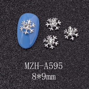 Detailed view of silver snowflake nail charms with rhinestone on blue false nails