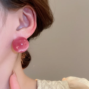 Close-up of pink round candy-colored stud earring with smooth glossy resin finish