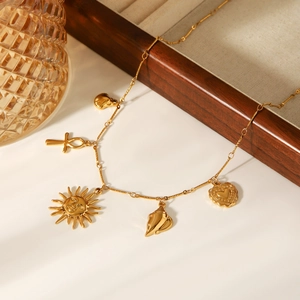 Detailed view of gold multi-pendant necklace with sun shell and heart charms on white surface