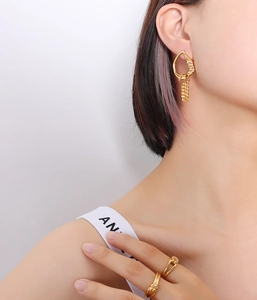 Detailed shot of irregular geometric gold fringe earrings and twisted ring on model