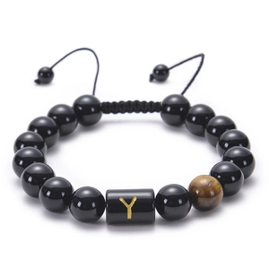 Detailed macro of black onyx bead bracelet featuring adjustable cord and gold Y letter charm
