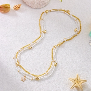 Macro shot of layered seed bead necklace with gold starfish and shell pendants