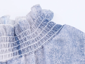 Détail du tissu mousseline tie-dye bleu clair avec texture froncée et bords volantés