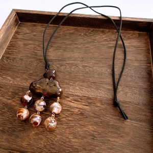Detail of amber resin beads and cloud pendant with marble pattern on wood
