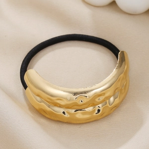 Detail of minimalist gold hammered metal hair tie on champagne silk background