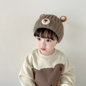 Detail of baby knit hat with cute bear ears and matching brown bear print sweatshirt