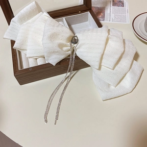Detail of white lace bow hair clip featuring a large grey gemstone and crystal tassels