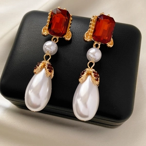 Detailed macro view of vintage gold earrings with red faceted gems and large pearl drops