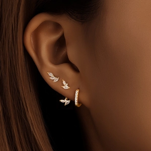 Detail of gold leaf earrings and pavé hoop set with white marquise zircons
