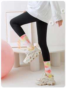 Close-up of colorful tie-dye pilates socks paired with white sneakers and yoga leggings
