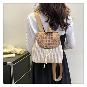 Detail of woven straw backpack showing vintage floral patterns and fringe drawstring closure