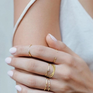 Detailed close-up of a three-layer intertwined golden open ring on a model's hand
