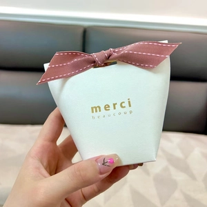 White textured gift box with pink bow ribbon and gold merci beaucoup lettering