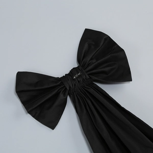 Close-up of a large black satin bow detail on a silver sequin evening gown dress