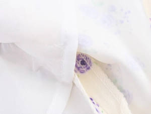 Vue macro détaillée du tissu satiné floral blanc avec imprimés de fleurs violettes