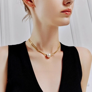 Collier élégant chaîne serpent dorée avec pendentif perle sur le cou d'un modèle