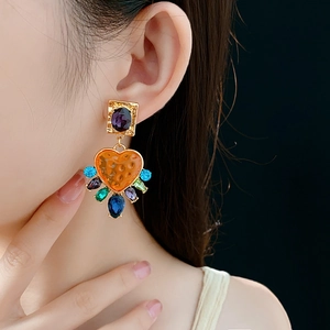 Détail d'une boucle d'oreille vintage avec gemme violette et cœur en résine orange