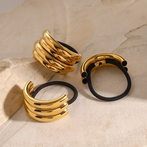 Set of 3 elastic hair ties with multi-layered gold metal tubes on natural stone background