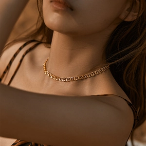Close-up of golden woven chain necklace with heavy metal texture on female model