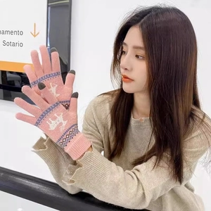 Detail of pink knitted winter gloves featuring touchscreen tips and reindeer pattern