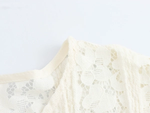 Close-up detail of white floral lace neckline and intricate fabric texture on dress