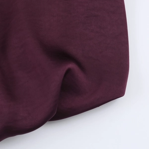 Detailed view of dark purple satin fabric with a smooth texture and glossy finish