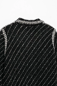 Close-up of black and white tweed knit jacket with textured weave and collar detail