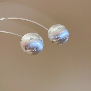 Detailed macro view of silver brushed metal stud earrings with star-shaped zircons