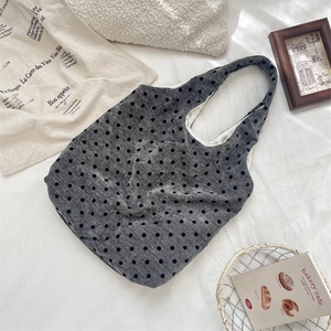 Detailed top view of large grey polka dot canvas tote bag on soft white bedding