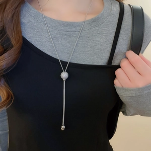 Detailed view of silver pavé zircon sphere pendant on sleek snake chain sweater necklace