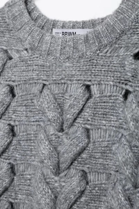 Macro view of cable knit pattern and ribbed neckline on a soft grey sweater