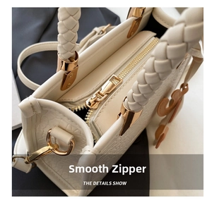 Detail showing smooth gold zipper and white woven handle on the fashionable handbag
