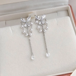 Macro shot of silver butterfly tassel earrings with zircon stones and pearl chains