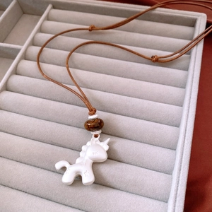 Détail du pendentif licorne blanc mat et perle brillante sur cordon marron réglable