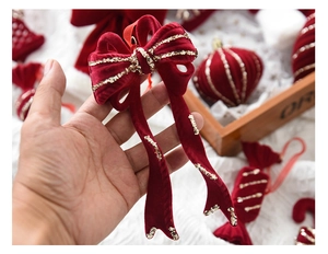 Close-up of red velvet bow Christmas ornament with gold sequins and hanging string