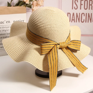 Close-up of beige woven straw hat featuring a striped bow detail on a stylish display