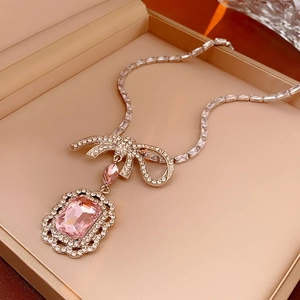 Détail du pendentif en cristal rose rectangulaire avec nœud en zircon dans son écrin à bijoux