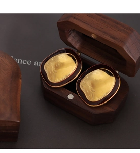 Detail of vintage textured gold earrings with dark enamel trim in a walnut wood box
