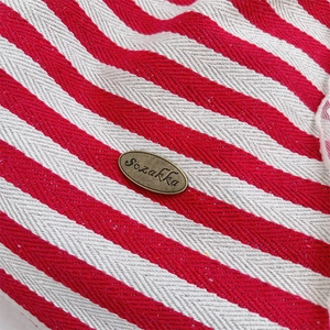 Close-up of red and white herringbone canvas fabric with oval bronze Sozakka logo