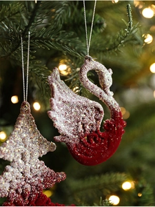Detail of red flocked swan and tree ornaments with snow-like glitter on a Christmas tree