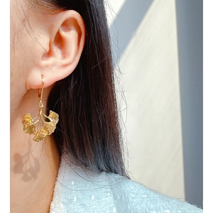 Artistic gold-plated ginkgo leaf dangle earrings on a female model with a vintage aesthetic