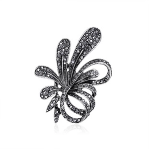 Macro shot of silver vintage brooch with black gemstone pavé and intricate floral details
