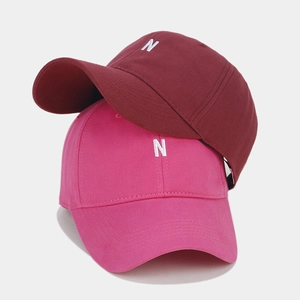 Close-up of burgundy and pink baseball caps featuring white embroidered N letter