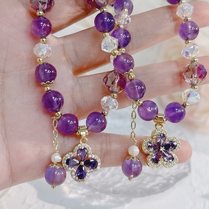 Macro detail of natural amethyst bracelet with zircon clover pendant and gold accents