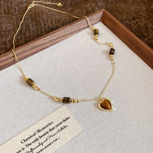 Detailed close-up of tiger eye heart pendant necklace with gold chain on vintage display